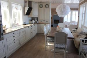 a kitchen with white cabinets and a table with chairs at Torshaug 4 bedroom cabin in Gol