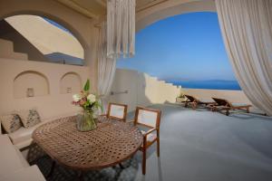 a room with a table with a vase of flowers on it at THE A COLLECTION by K&K in Oia