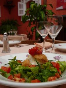 een bord eten op een tafel met wijnglazen bij Au Soleil d'Or in Pontaubert