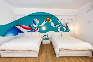 a bedroom with two beds with a mural on the wall at Traveller Inn - Mido Hotel in Taitung City