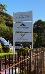 a sign in a parking lot next to a fence at Glenlochy Nevis Bridge Apartments in Fort William