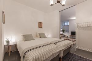 ein weißes Schlafzimmer mit einem großen Bett und einem Spiegel in der Unterkunft Renovated Apart with Private Courtyard, By TimeCooler in Lissabon