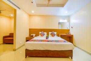 um quarto com uma cama e uma cadeira em FabExpress Deccan Heritage Abids em Hyderabad