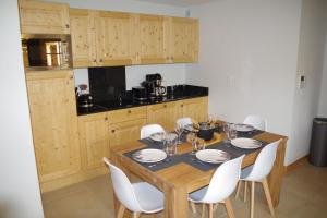 a kitchen with a wooden table and white chairs at Résidence : Le Crystal Chalet in Les Deux Alpes
