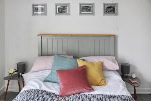 ein Schlafzimmer mit einem Bett mit bunten Kissen darauf in der Unterkunft Secret Cottage, Wivenhoe - Charming, Cosy, Convenient & Quiet, 2 x Double Bed Period Cottage PLUS Patio - 6 min walk train, 2 min walk High Street Pubs, Restaurants, Shops in Wivenhoe