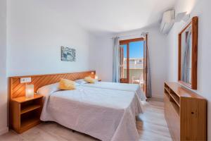 a white bedroom with a bed and a window at Apartamento Bressol D in Port de Pollensa +11 photos