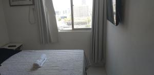 a bed with a towel on it in a room with a window at Centro, Privado total, Metrô, rodoviária, Copacabana em 10 minutos, SmarTV in Rio de Janeiro