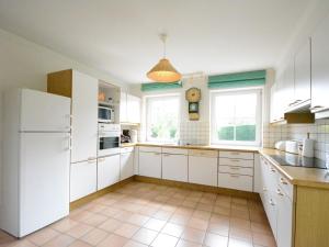 cocina con armarios blancos y nevera blanca en Spacious villa in Daverdisse with large garden, en Daverdisse