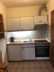 een kleine keuken met witte kasten en een wastafel bij Ferienwohnung-Op-n-Rugenbarg-70-OG in Cuxhaven