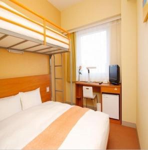 a bedroom with a bed and a desk with a television at Smile Hotel Sendai Izumi IC in Sendai