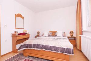 a bedroom with a wooden bed and a table and a mirror at Guesthouse Relax and Fly Sarajevo in Sarajevo