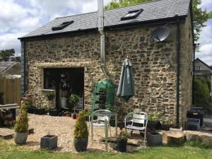 a stone building with an umbrella and chairs and plants at LYDONIA BARN in Lydford