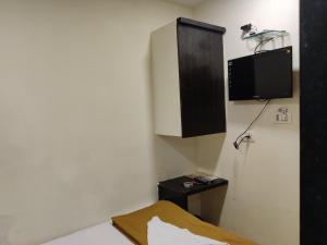 a room with a bed and a tv on the wall at Hotel Golden Sagar - Kurla in Mumbai