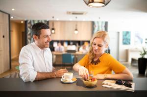 a man and a woman sitting at a table eating food at Three Corners Lifestyle Hotel in Budapest