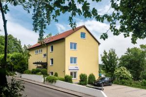 une maison jaune avec une voiture garée devant elle dans l'établissement Apartmenthaus am Erlbach, à Buch am Erlbach