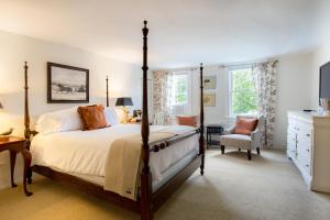 a bedroom with a four poster bed and a chair at Kedron Valley Inn in Woodstock