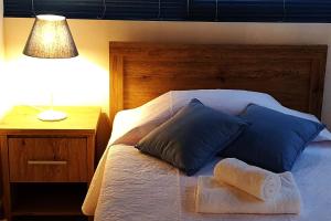 łóżko z 2 niebieskimi poduszkami i stolikiem nocnym z lampką w obiekcie EasyStay Two Bedroom Apartment w Larnace