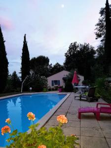 een zwembad met een tafel, een stoel en bloemen bij studio Côté Sud vert in Sarlat-la-Canéda