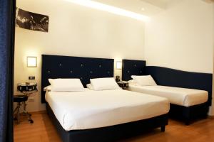 two beds in a hotel room with white sheets at Hotel Franklin Feel The Sound in Rome