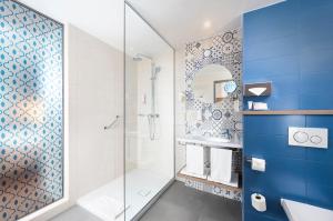 a bathroom with a shower, sink, and mirror at The Three Corners Lifestyle Hotel in Budapest
