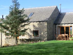 una casa de piedra con césped delante en Hartcliffe Retreat, en Penistone