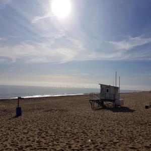 a life guard shack on a beach with the sun at 185 Belle Aire, Beach Road, Hemsby, Norfolk, NR29 4HZ in Hemsby