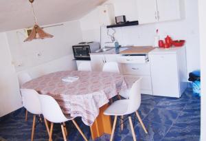 uma pequena cozinha com uma mesa e cadeiras brancas em Chardak Neither in the Sky nor on the Ground em Jagodina