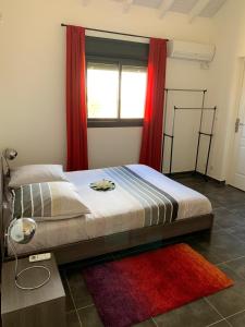 a bedroom with a bed with red curtains and a red rug at MALAKA F1 TOUT CONFORT Le Moule avec Piscine in Le Moule