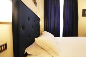 a bed with a black headboard and blue curtains at Hotel Franklin Feel The Sound in Rome