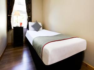 a bedroom with a bed with a pillow and a window at Auld Mill House Hotel in Dunfermline