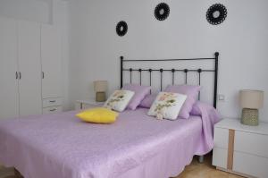 Un dormitorio con una cama con sábanas y almohadas púrpuras. en Alenia Apartments, en Alicante
