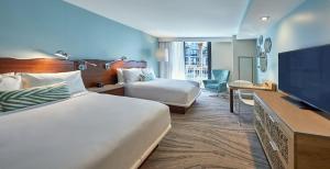 a hotel room with two beds and a flat screen tv at Zota Beach Resort in Longboat Key