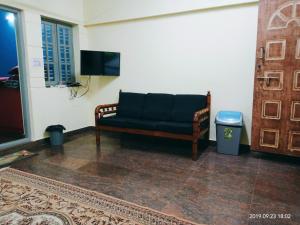 a black couch sitting in a room with a tv at Freshup & Stay in Chikmagalūr