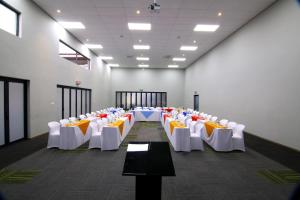Cette chambre comprend des rangées de tables et de chaises blanches. dans l'établissement Travelodge Kasane, à Kasane