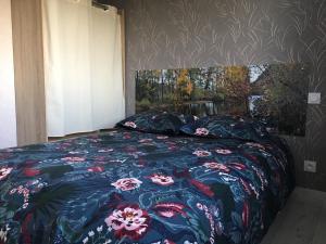 sypialnia z łóżkiem z narzutą kwiatową w obiekcie Gîte aux Portes d'Aubrac w mieście Salgues