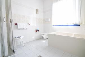 e bagno bianco con vasca, servizi igienici e lavandino. di MyLago Hotel a Riva del Garda