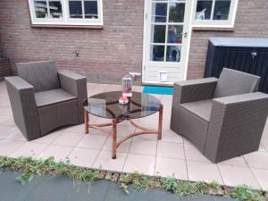 three wicker chairs and a glass table on a patio at Dendolili room in Amsterdam