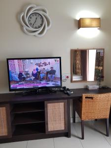a television on a desk with a clock on the wall at Gold Coast Morib Ain Studio in Kampong Tanjong Pechah
