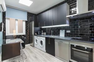 a kitchen with black cabinets and a washer and dryer at Plaza Mayor Apartment in Madrid