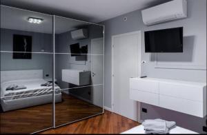 Habitación con mampara de cristal, cama y TV. en Le residenze dell'Adda en Cassano dʼAdda