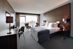 a hotel room with a bed, desk, chair and a lamp at Van der Valk Hotel Sassenheim - Leiden in Sassenheim