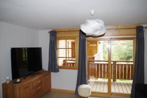 a living room with a television and a balcony at Résidence : Le Crystal Chalet in Les Deux Alpes