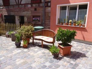 a bench sitting in front of a building with potted plants at Landhauspension Rank in Bad Berka