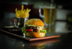 a hamburger on a plate with a glass of beer at Riff Hikkaduwa in Hikkaduwa