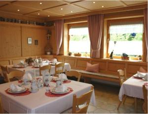 una sala da pranzo con tavoli e sedie bianchi e finestre di Gästehaus Sonja a Durach