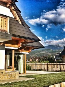 a house with a wooden fence and mountains in the background at Cubrynka in Zakopane
