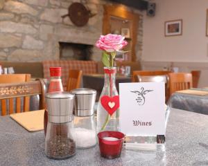 a table with a vase with a pink rose in it at The Dunning Hotel in Perth