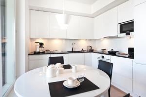 a white kitchen with a white table and chairs at Aallonkoti Apartments in Helsinki