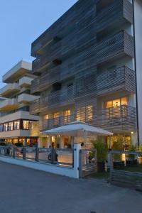 un palazzo alto con un ombrello davanti di Kiss Beachfront Hotel & Restaurant a Cervia