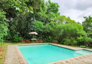 - Piscina con mesa y sombrilla en Impala Niezel Lodge & Guest House, en Hazyview